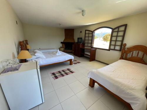a large room with two beds and a window at Pousada Bela Mauá in Itatiaia