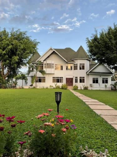 Una gran casa blanca con flores en el patio. en Amala villas, en Arusha
