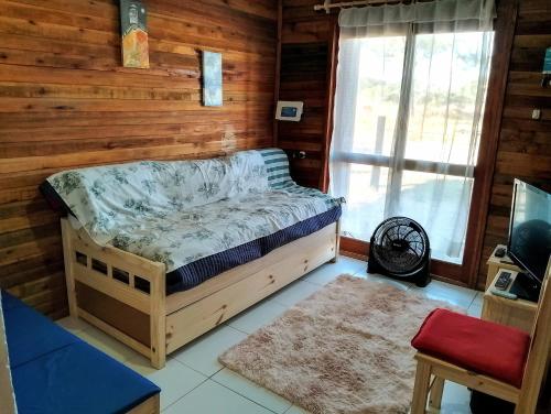 a bedroom with a bed in a room with wooden walls at Cabaña Faro di luce in Santa Vitória do Palmar