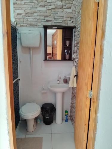 a bathroom with a sink and a toilet and a mirror at Cabaña Faro di luce in Santa Vitória do Palmar