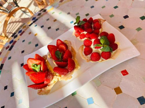 two plates of food with strawberries on a table at Villa'S in Zaouiet Bouzarktoune