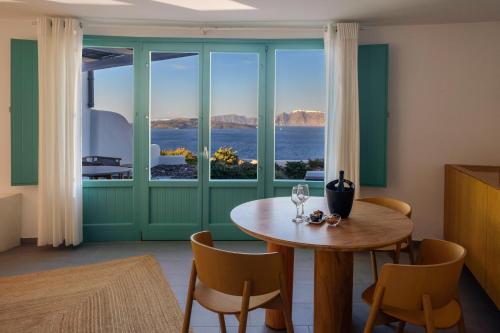 a dining room with a table and a large window at Neptune Luxury Suites in Akrotiri
