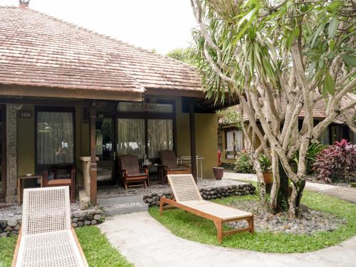 two chairs and a bench in front of a house at Peneeda View Beach Hotel in Sanur