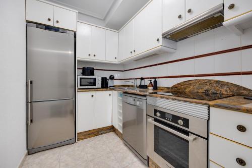 kuchnia z białymi szafkami i urządzeniami ze stali nierdzewnej w obiekcie CB Living - Cozy condo with patio, Playa Flamenca w mieście Orihuela Costa