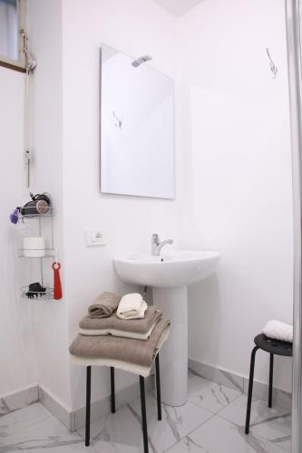 a white bathroom with a sink and a towel on a stool at Il Gatto e La Volpe Foresteria Lombarda in Lierna