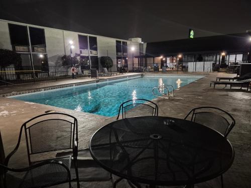 a table and chairs next to a swimming pool at night at Abilene Whitten Inn in Abilene