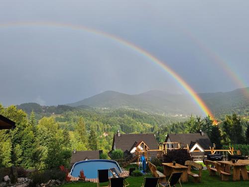 a rainbow over a yard with a tent and tables at Zawoja Nad Koroną z jacuzzi in Zawoja
