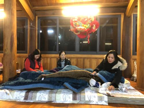 a group of three women sitting on a bed at Nhà gỗ Mộc châu Panorama in Mộc Châu