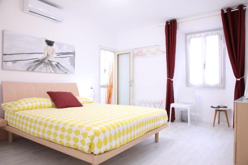 a bedroom with a yellow and white bed and windows at Il Gatto e La Volpe Foresteria Lombarda in Lierna
