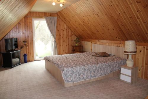 a bedroom with a bed in a room with wooden walls at Mažasis SPA in Merkinė
