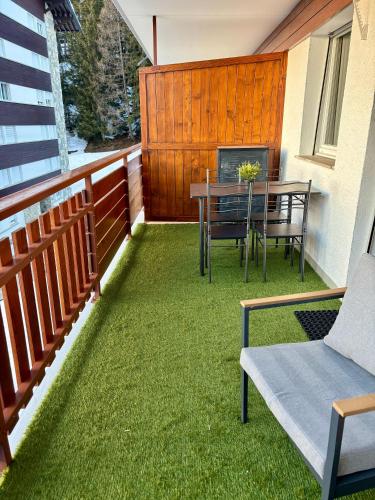 a patio with a table and chairs on the grass at Studio au Cœur des Sommets in Crans-Montana