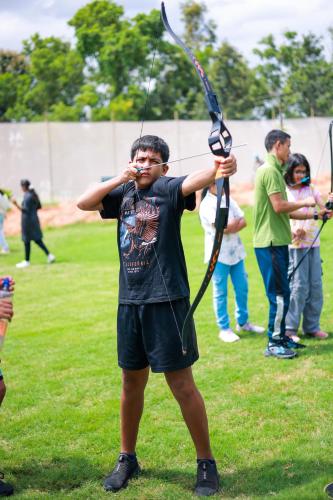 a man holding a bow and arrow in a field at Quad Club - Resort and Spa, Nandi Hills in Nandigunda