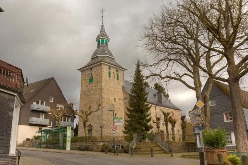 a building with a tower with a cross on it at Landgasthof Tönnes in Wipperfürth