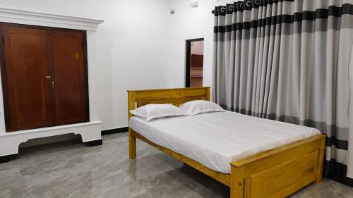 a bedroom with a wooden bed and a dresser at Gunam guest house in Point Pedro