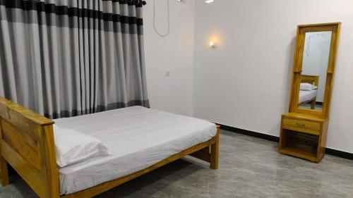 a small bedroom with a bed and a mirror at Gunam guest house in Point Pedro