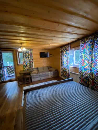 Un dormitorio con una cama grande en una habitación con ventanas. en Сімейний номер 2 Садиба У Ані, en Synevyrsʼka Polyana
