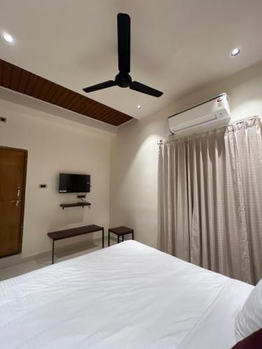 a bedroom with a white bed and a ceiling fan at Hotel GMR Pearls in Srikalahasti