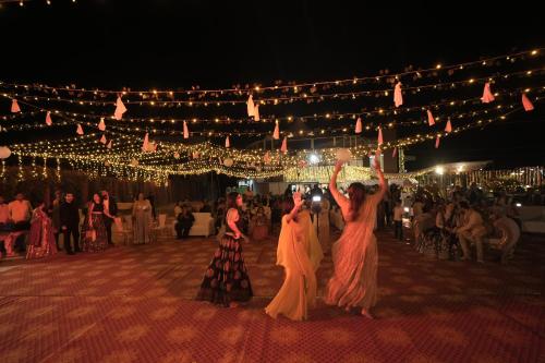 two women are dancing in front of a crowd of people at Quad Club - Resort and Spa, Nandi Hills in Nandigunda