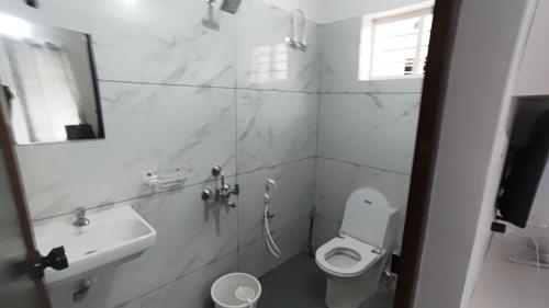 a white bathroom with a toilet and a sink at Sivasylam rooms in Trivandrum