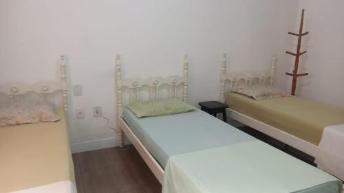 three beds in a room with white walls at Casa acolhedora e familiar in Campos dos Goytacazes