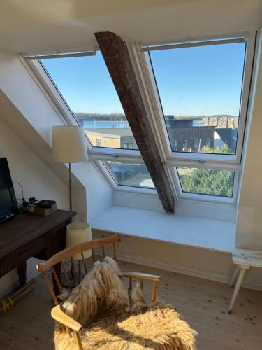 a room with three windows and a chair and a desk at Holiday Home Penthouse Lemvig in Lemvig