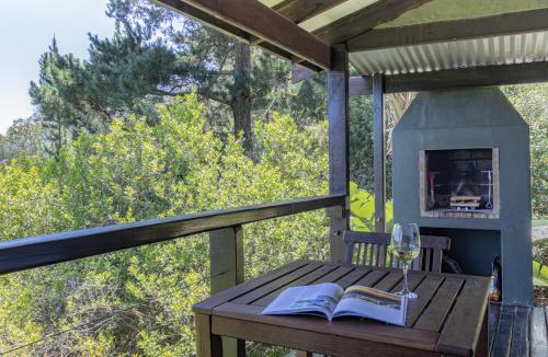 a table with a book and a glass of wine at Forest Valley Cottages in Knysna