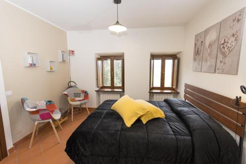 a bedroom with a large black bed and chairs at SAILA Monolocale VENERE in Attigliano