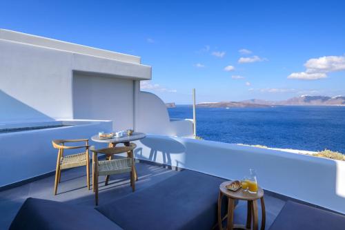 a balcony with tables and chairs and the ocean at Neptune Luxury Suites in Akrotiri