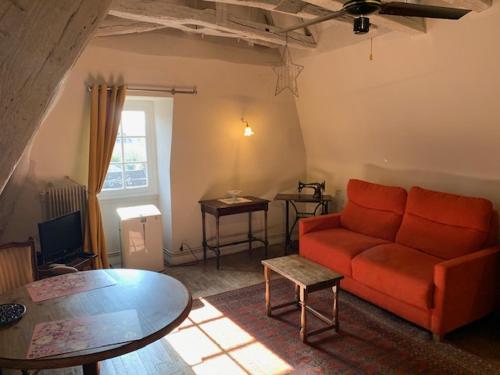 un salon avec un canapé rouge et une table dans l'établissement Loft Montaigne Cité médiévale Sarlat, à Sarlat-la-Canéda