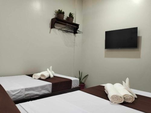 two beds in a room with a tv at JMorino Pension House in Puerto Princesa City