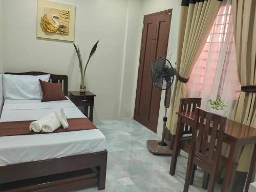 a bedroom with a bed and a desk and a window at JMorino Pension House in Puerto Princesa City