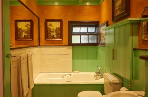 a green bathroom with a tub and a toilet at TwoAngels in Knysna