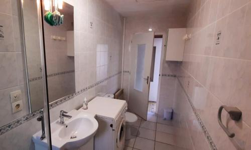 a white bathroom with a sink and a toilet at Maison de pêcheur in Brem-Sur-Mer