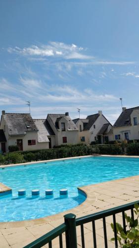 une grande piscine bleue avec des maisons en arrière-plan dans l'établissement Maison Batz sur Mer Presqu'île de Guérande, à Batz-sur-Mer