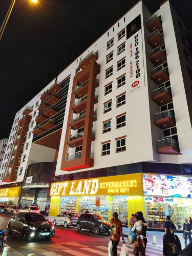 a large building with cars parked in front of it at Tabs Dubai Hostel in Dubai