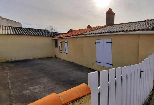 a building with a white fence and a parking lot at Maison de pêcheur in Brem-Sur-Mer