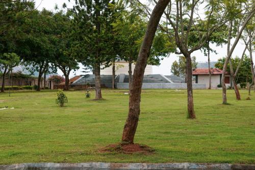 a group of trees in a park with a building at Quad Club - Resort and Spa, Nandi Hills in Nandigunda