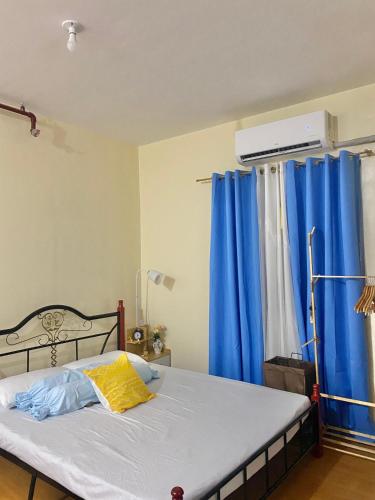 a bedroom with a bed with blue curtains and a window at Classy Condo in CDO in Cagayan de Oro