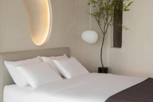 a white bed with white pillows and a potted tree at Ziggy Hotel in Changsha