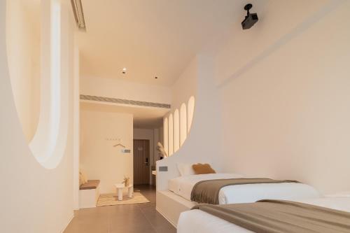 a white bedroom with two beds and a window at Ziggy Hotel in Changsha