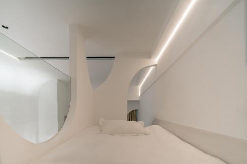 a white room with a bed and a mirror at Ziggy Hotel in Changsha