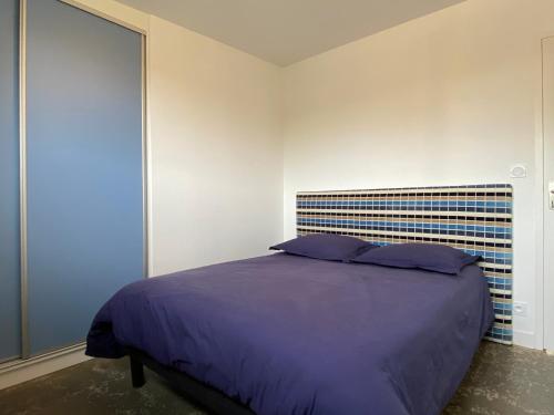 - une chambre avec un grand lit et des oreillers violets dans l'établissement Loregate, à Jullouville
