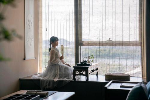 a young girl sitting in a window looking out at Ziggy Hotel in Changsha