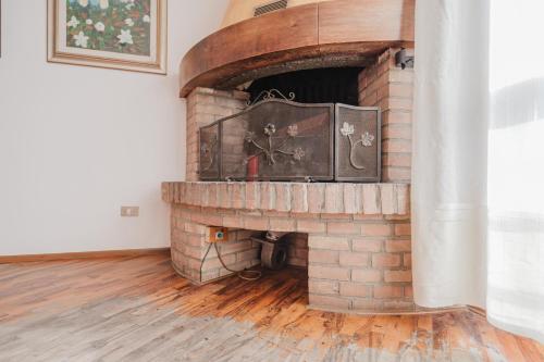 a brick fireplace in a room with a wooden floor at Residence Gerlin - 10 minuti da Valdobbiadene & Parking in Colbertaldo