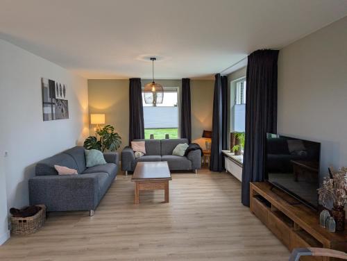 a living room with two couches and a tv at Vrijstaande Landelijke Woning in Slagharen