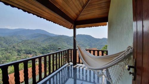 a hammock on a balcony with a view of mountains at Pousada Bela Mauá in Itatiaia