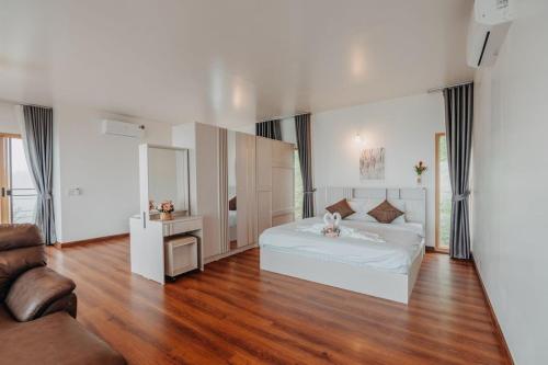 a bedroom with a white bed and a wooden floor at Mon Sai Lom ม่อนสายลม ม่อนแจ่ม in Mon Jam