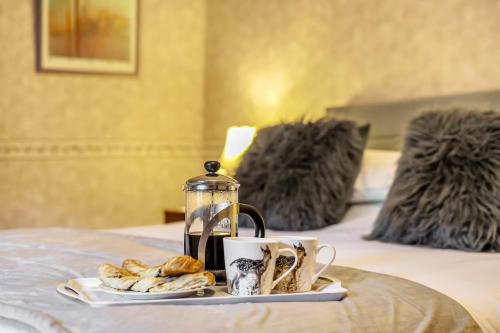a tray with a tea kettle and a plate of croissants at 18th Century Farmhouse, England Wales Border, Breathtaking Views in Oswestry