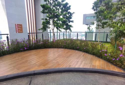 a wooden floor in front of a building with purple flowers at MJ Homestay 99 Batu Caves KL North 99Residence 3R2B in Kuala Lumpur