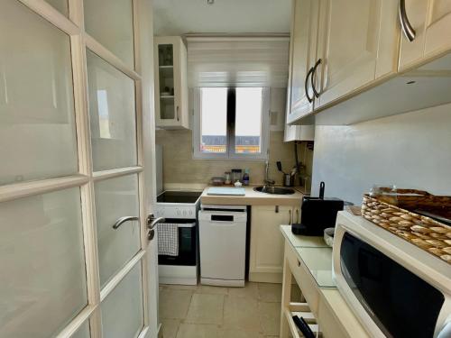 - une petite cuisine avec des appareils électroménagers blancs et une porte dans l'établissement Charmant Appartement 16eme, à Paris